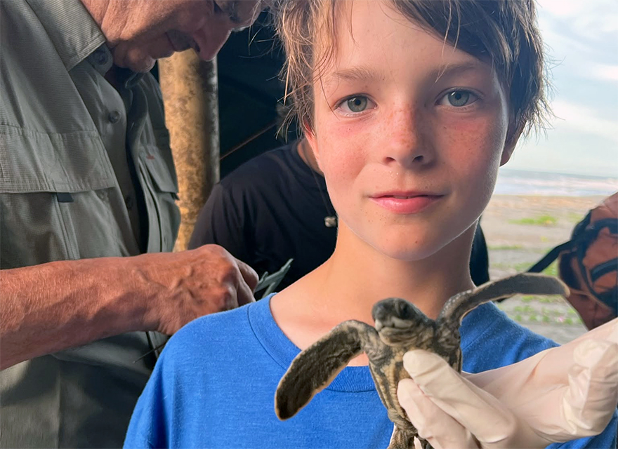 child holding baby sea turtle in Costa Rica