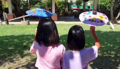 Back view of two Thai girls holding traditional umbrellas