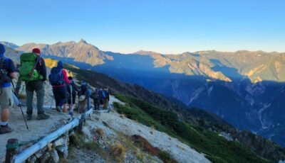 group hiking through mountains with backpacks and trekking poles during charity challenge.