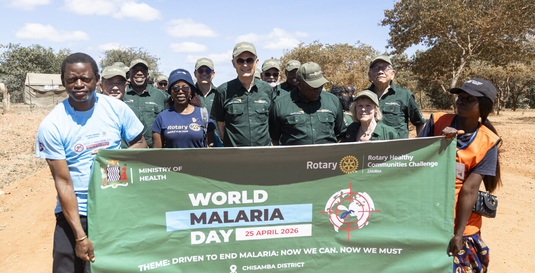 donor trip group holds a world malaria day banner while on the ground in Zambia.