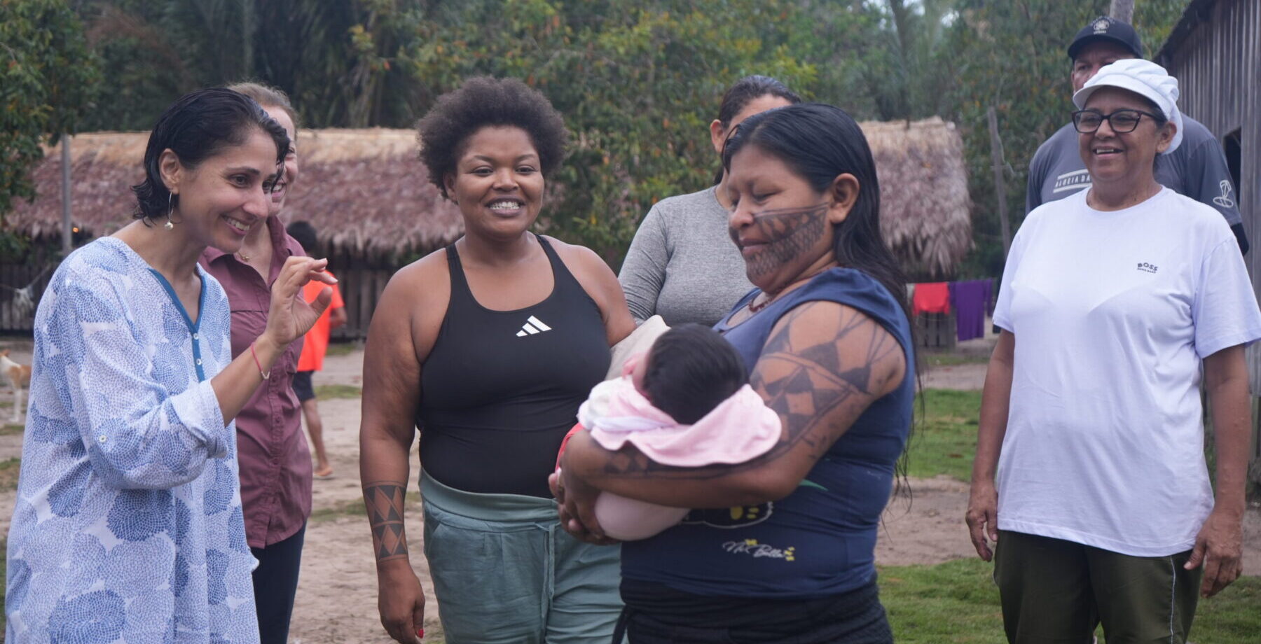 donor trip group gathers around an indigenous community member and waves at the baby she is carrying.
