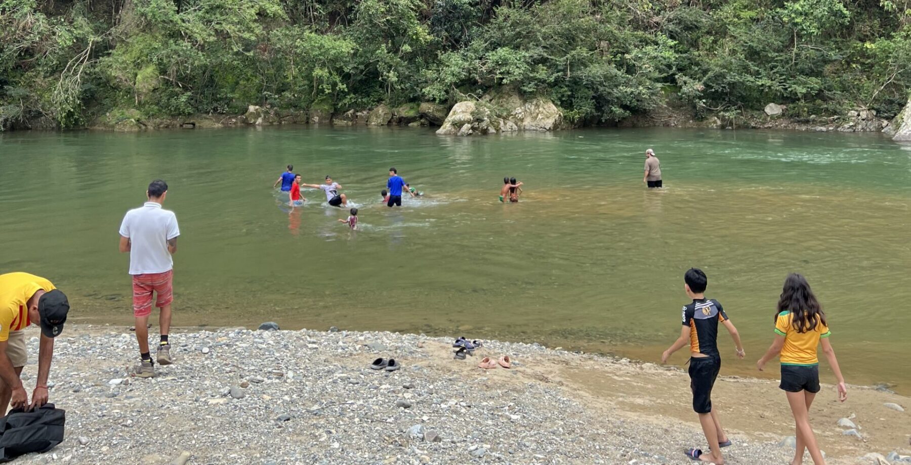 children from Panama City and the Emberá community play together in a river within a rainforest in Panama.