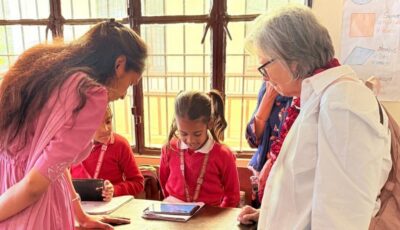 woman on a donor travel trip talks with a student and teacher at a school.