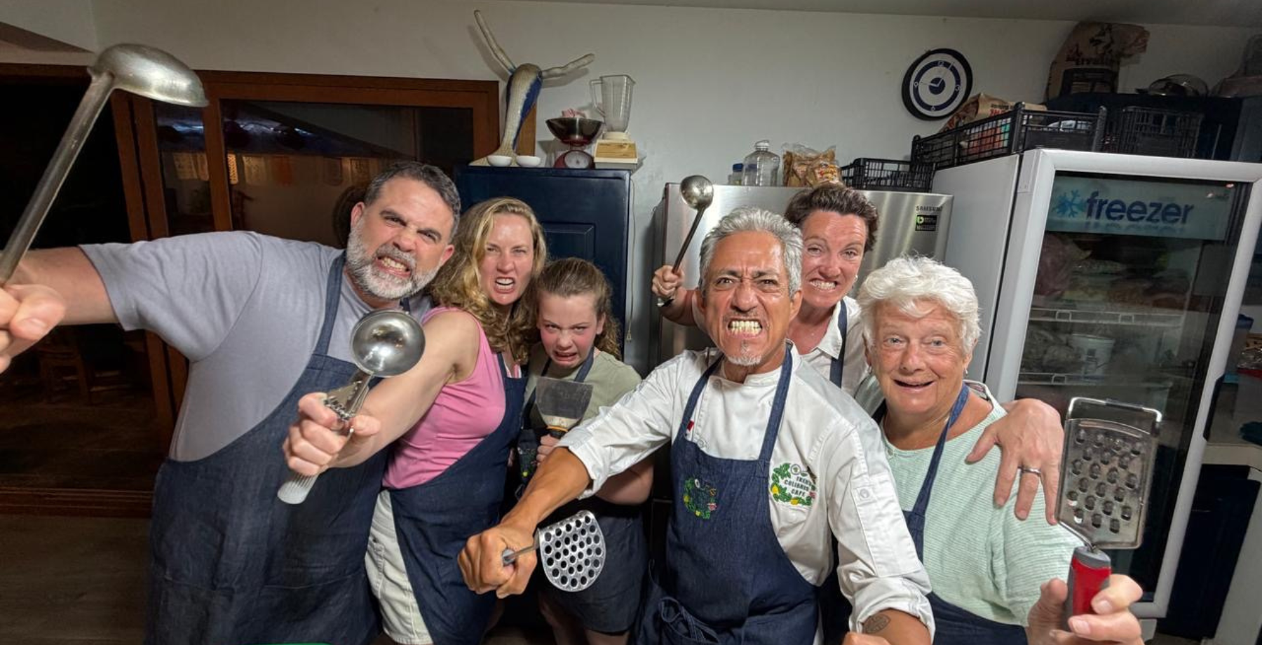 family smiling for a photo showing kitchen utensils.